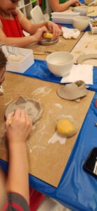 Pottery class participants engaged in a collaborative project, molding a large clay sculpture.