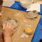 Pottery class participants engaged in a collaborative project, molding a large clay sculpture.